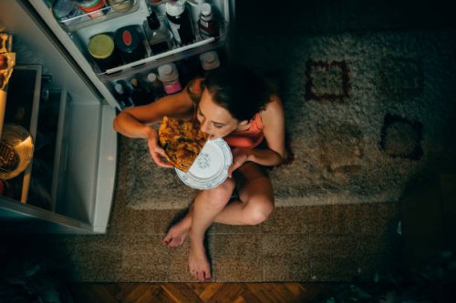 woman eating in front of the refrigerator in the kitchen late night - junk food stock pictures, royalty-free photos & images