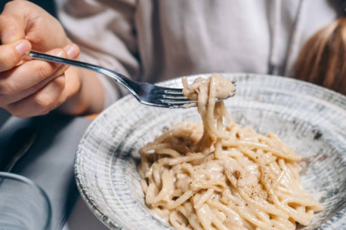 woman eats spaghetti in cheese sauce with black pepper at restaurant . traditional roman pasta cacio e peppe in italy, italian cuisine recipes - food stock pictures, royalty-free photos & images
