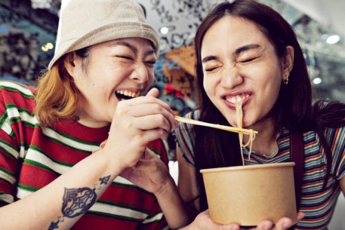 woman feeding noodles with chopsticks to friend - travel stock pictures, royalty-free photos & images