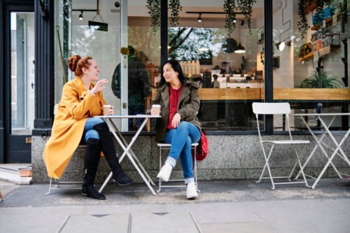 woman gesturing while talking with female friend outside coffee shop - coffee stockfoto's en -beelden