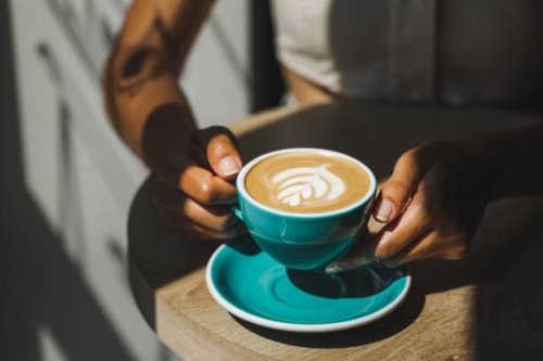 woman hands holding cup of fresh cappuccino close up. beautiful natural sun light in cafe - coffee stockfoto's en -beelden