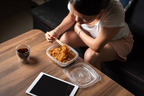 woman having takeaway fried noodles meal at home - junk food stock pictures, royalty-free photos & images