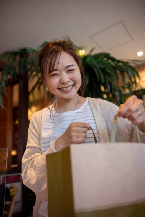 woman holding a paper bag in cafe - looking at camera - junk food stock pictures, royalty-free photos & images