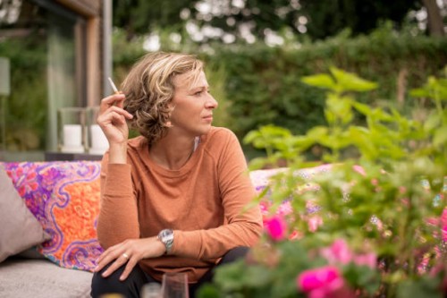 woman holding cigarette while sitting on sofa at backyard - garden decoration photos et images de collection