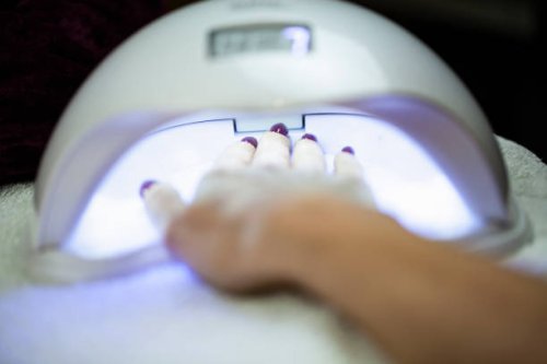 woman holding her hand under a uv lamp to set the nail polish - nails art stock pictures, royalty-free photos & images