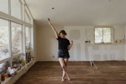 woman holding paintbrush and dancing in new home - home decoration stock pictures, royalty-free photos & images