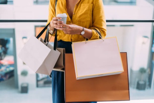 woman holding shopping bags and coffee in a mall - fashion stock pictures, royalty-free photos & images