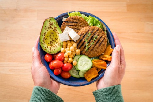 woman holds a plate with healty plant-based food - food stock pictures, royalty-free photos & images