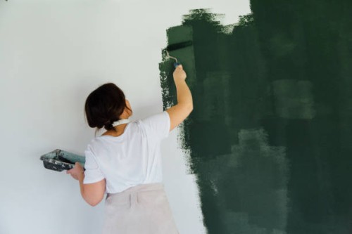 woman in head phones painting white wall in green color - home decoration stock pictures, royalty-free photos & images