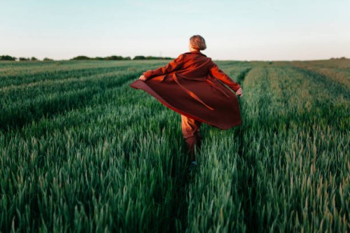 woman in red coat walking in the field at sunset - fashion stock pictures, royalty-free photos & images