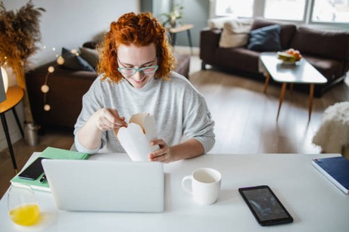 woman is taking a lunch break while working from home - junk food stock pictures, royalty-free photos & images