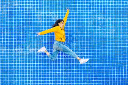 woman jumping in front of a blue background - fashion stock-fotos und bilder