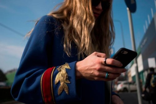 Woman looks at her mobile phone prior to the women's Fall/Winter 2018/2019 collection fashion show by Gucci in Milan, on February 21, 2018. / AFP...