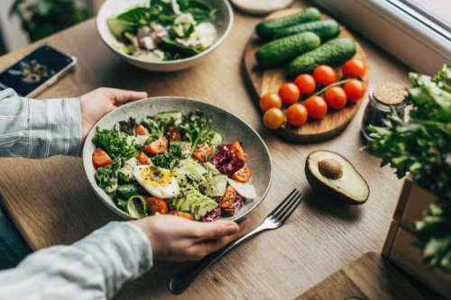 woman mixing delicious superfood salad ingredients with wooden spoons in kitchen - food stock pictures, royalty-free photos & images