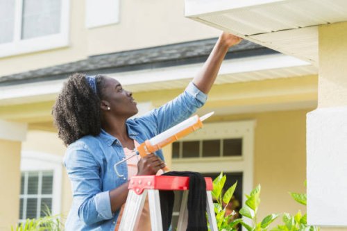 woman on ladder outside house doing repairs - home decoration stock pictures, royalty-free photos & images