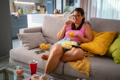 woman on the sofa watching tv and eating unhealthy food snack - junk food stock pictures, royalty-free photos & images