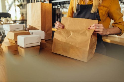 woman packing food in paper bags - junk food stock pictures, royalty-free photos & images