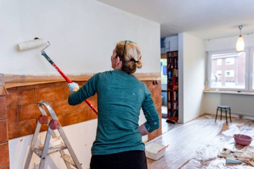 woman painting the kitchen wall using paint roller - home decoration stockfoto's en -beelden