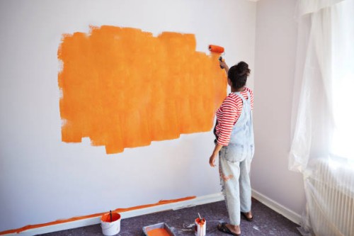 woman painting wall while renovating home - home decoration stockfoto's en -beelden