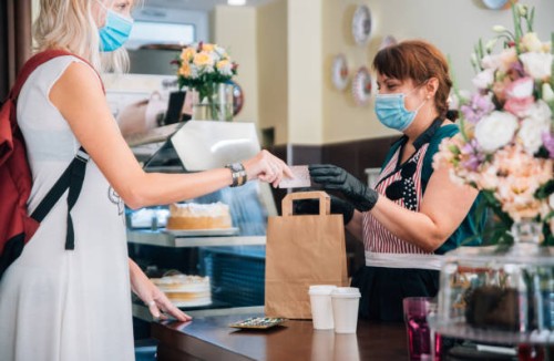 woman paying for takeaway food bag and a coffee cups during covid-19 - junk food stock pictures, royalty-free photos & images