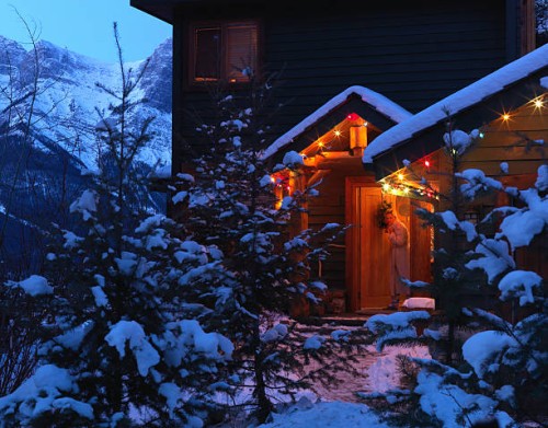 woman peering at snowy front yard from doorway decorated in christmas lights at dawn - garden decoration stock pictures, royalty-free photos & images