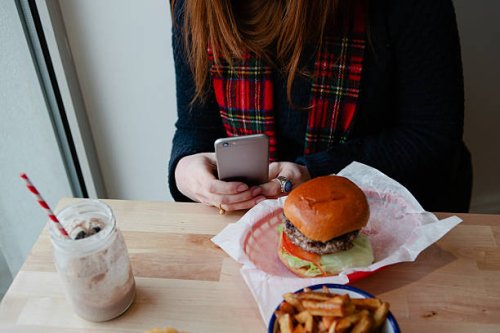 woman photographing a plate of junk food - junk food fotografías e imágenes de stock
