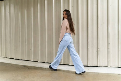 woman posing on move standing looking the camera and smiling in front of wall - fashion stock pictures, royalty-free photos & images