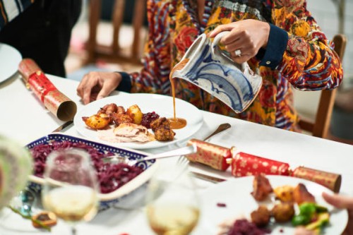 woman pouring gravy onto roast dinner with christmas crackers on table - food stock pictures, royalty-free photos & images