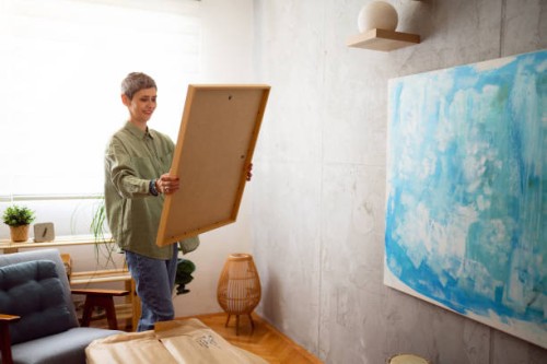 woman preparing a new painting to hang it on the wall - home decoration stock pictures, royalty-free photos & images