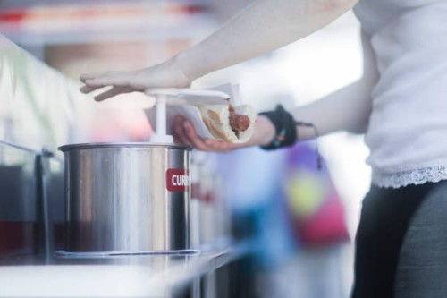 woman putting curry sauce on a hotdog - junk food stock-fotos und bilder