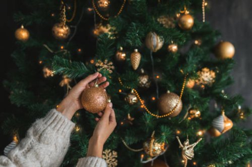 woman putting on christmas tree golden ornaments. - home decoration stock pictures, royalty-free photos & images