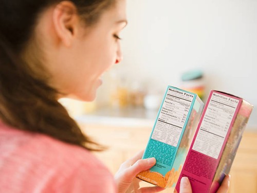 woman reading nutrition facts on food packaging - food stockfoto's en -beelden