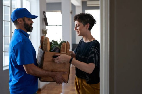 woman receiving groceries from delivery person - food stock pictures, royalty-free photos & images