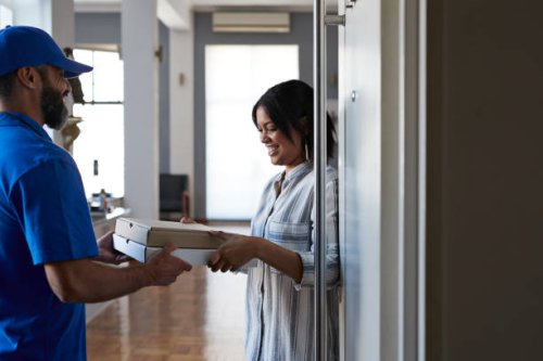 woman receiving pizza from delivery person - junk food stock pictures, royalty-free photos & images