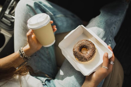woman relaxing in car and holding cup of coffee and paper box with chocolate donut - junk food stock pictures, royalty-free photos & images