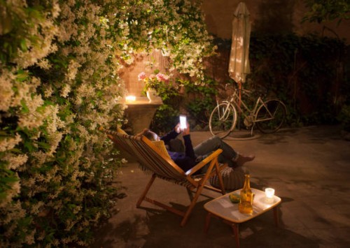 woman relaxing on deck chair in backyard at night, holding mobile phone - garden decoration photos et images de collection