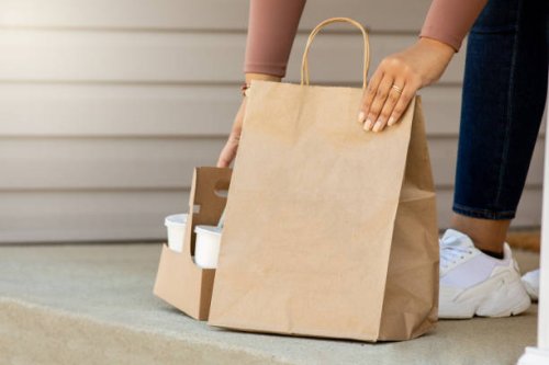 woman retrieves takeout food order front her front porch after it is delivered - junk food stock pictures, royalty-free photos & images