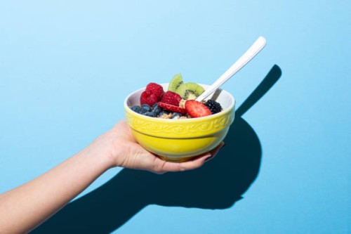 woman's hand holding bowl with muesli - food stock pictures, royalty-free photos & images
