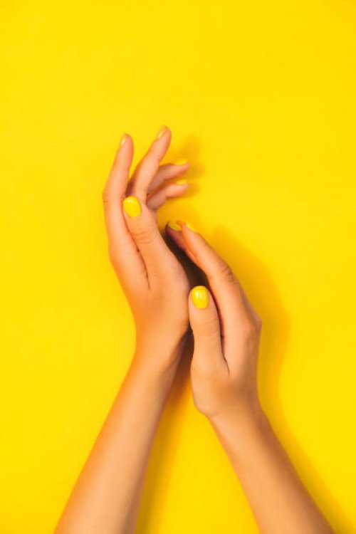 woman's hands with bright manicure are lying on yellow background. trendy colors of the year - nails art stock pictures, royalty-free photos & images