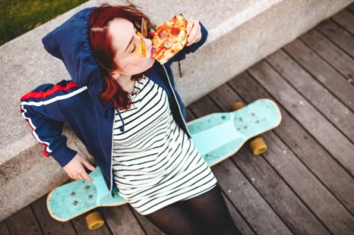 woman sitting on long board and eating pizza - junk food stock pictures, royalty-free photos & images