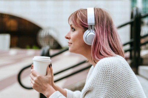 woman sitting on stairs with coffee and headphones - junk food stock pictures, royalty-free photos & images