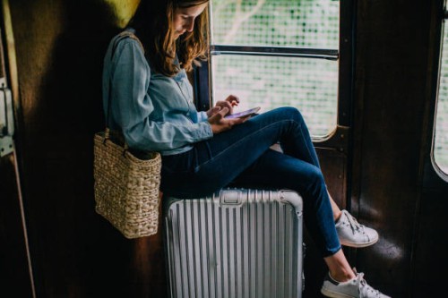 woman sitting on suitcase in train looking at smart phone - travel stock pictures, royalty-free photos & images