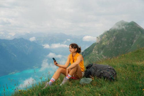 woman sitting on the meadow in swiss alps using smartphone during the hike - travel stock pictures, royalty-free photos & images