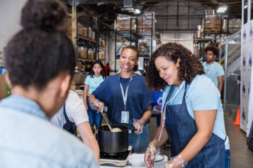 woman smiles at friend while preparing food for hungry - food stock pictures, royalty-free photos & images