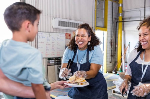 woman smiles while serving young food bank client - food stock pictures, royalty-free photos & images