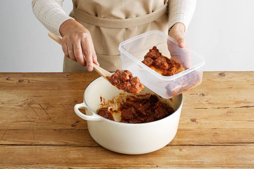 woman spooning meat into tupperware - food stock pictures, royalty-free photos & images