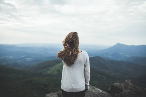 woman stares out at a beautiful mountain scene - fashion stock-fotos und bilder