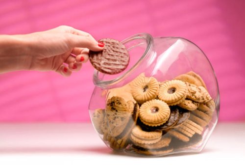 woman stealing biscuit, caught in the act. - junk food stock pictures, royalty-free photos & images