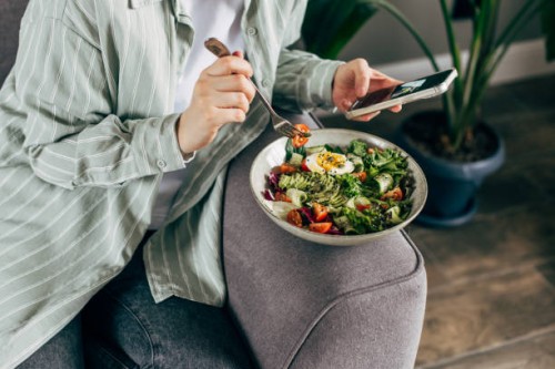 woman taking photo of fresh, spring, vegetable salad with smartphone. using phone while eating lunch. lifestyle trend - posting and sharing food pictures (images) on social media. - junk food stock pictures, royalty-free phot