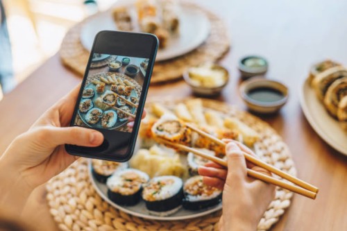 woman taking photo of maki sushi with smartphone - junk food stock pictures, royalty-free photos & images